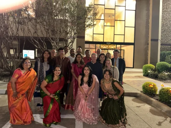 Vibrant cultural celebration with joyful individuals in traditional attire outside a modern venue.