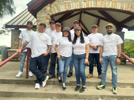 Team gathering in a park with diverse members in matching shirts and caps, promoting unity.