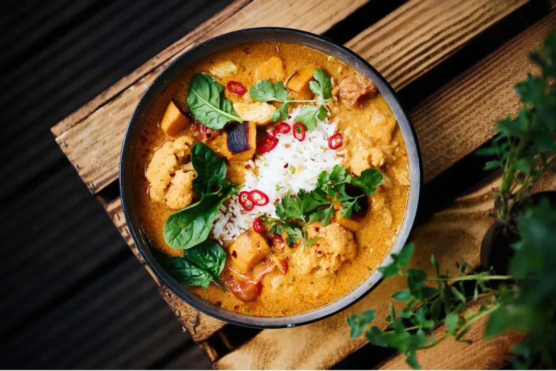 Professional Thai red curry with shrimp, jasmine rice, fresh cilantro, and red chilies in a modern bowl presentation.